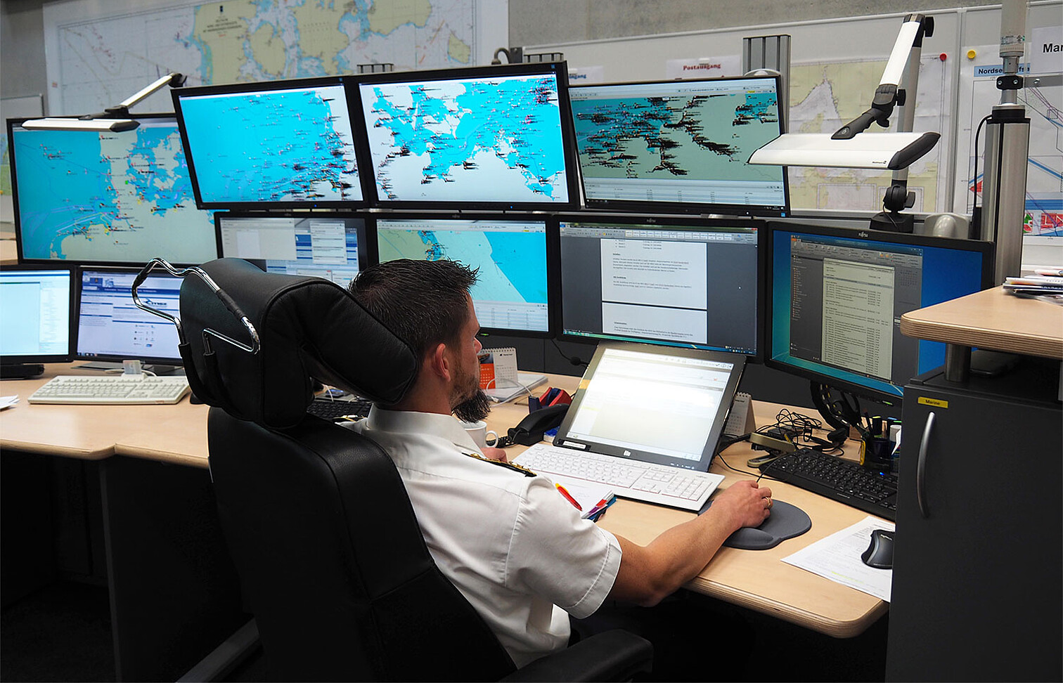 Marinesoldat am Schreibtisch vor mehreren Bildschirmen mit Datendarstellungen