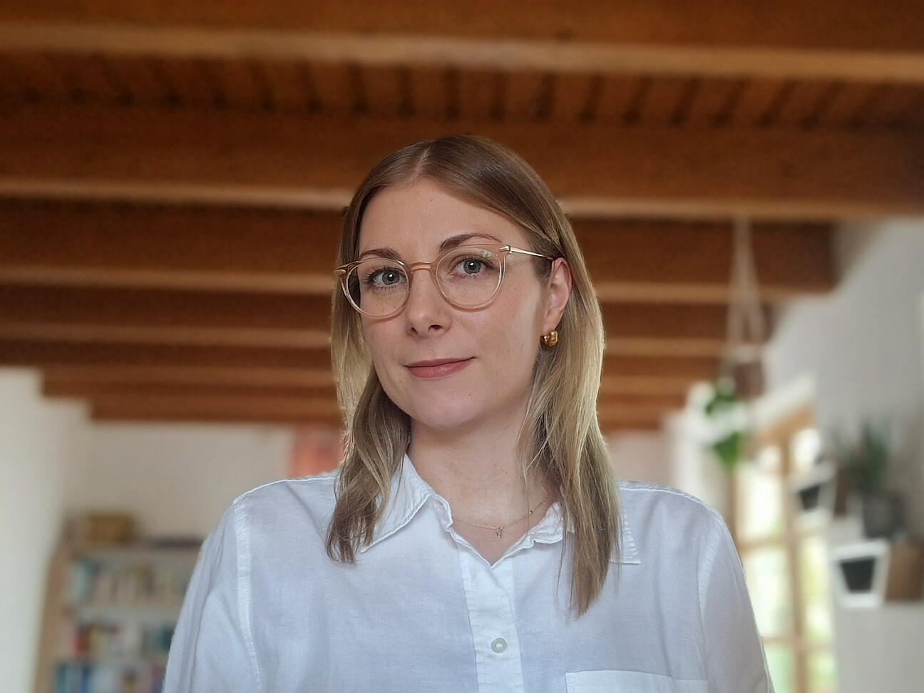 Junge Frau mit Brille schaut in die Kamera