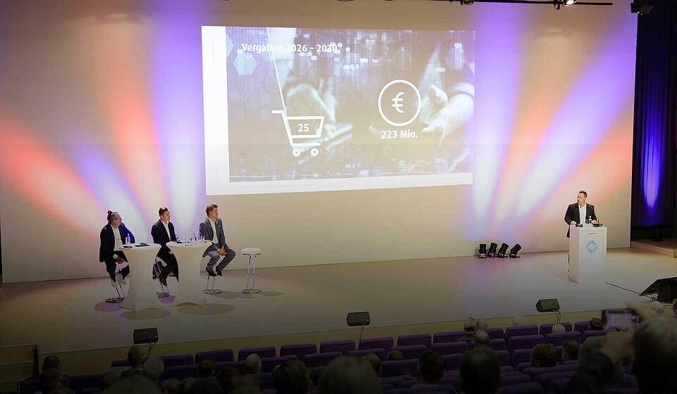 Bild von der Bühne auf den IndustryDays mit Folie zu den Vergabezeiträumen