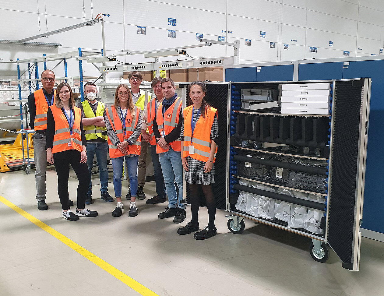Mitarbeitende der BWI und ihres Logistikpartners Geodis bei der Ansicht des zu erprobenden Transportwagens
