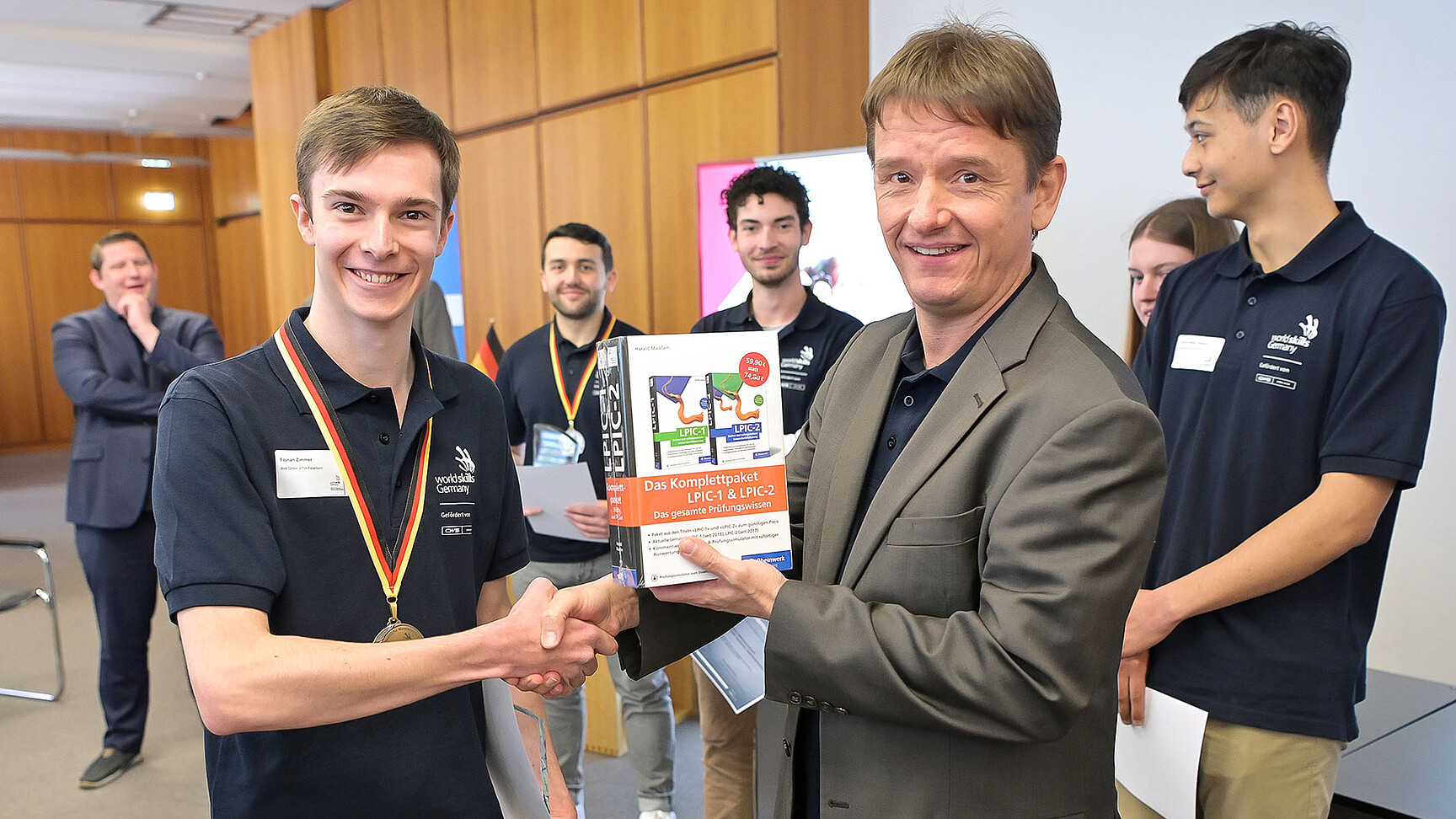 Florina während der Verleihungszeremonie. Er hat die Medaille um und bekommt ein Buch geschenkt.