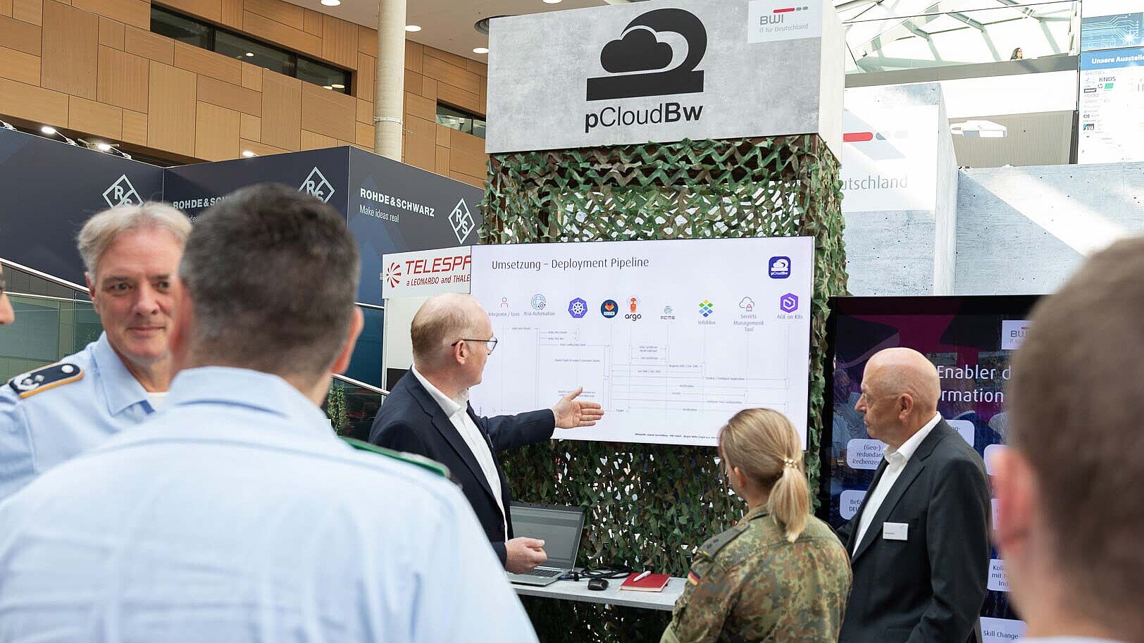BWI-Mitarbeitende erklären Bundeswehrangehörigen am Messestand der AFCEA 2024 die Funktionsweise der pCloudBw