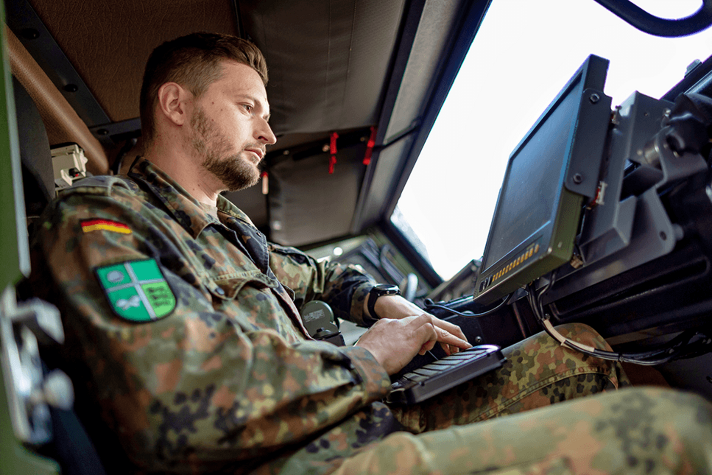 Ein Soldat sitzt vor dem Bediengerät für das Battle Management System in einem Fahrzeug